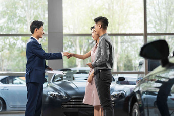 汽车销售人员和青年夫妇<strong>握手</strong>协助写实场景
