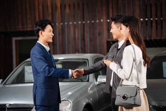 汽车销售人员和青年夫妇握手户内写实照片