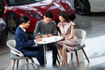 汽车销售人员与青年夫妇确认购车意向选择高清图片