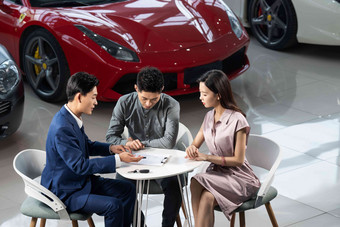 <strong>汽车</strong>销售人员与青年夫妇确认购车意向中国相片
