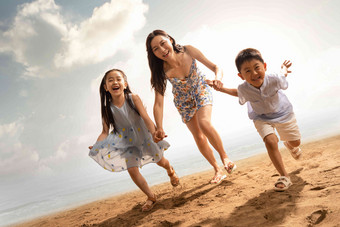 年轻母亲牵着两个孩子在沙滩上<strong>奔跑</strong>