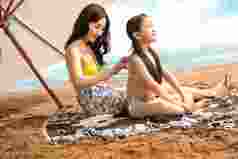 幸福母女在沙滩上擦防晒霜