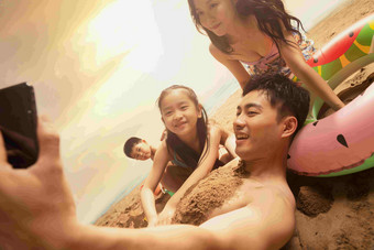 沙滩上男人拿手机和妻子孩子自拍可爱的镜头