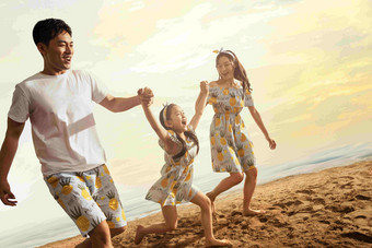 幸福的一家三口在沙滩上散步手牵手高清图片