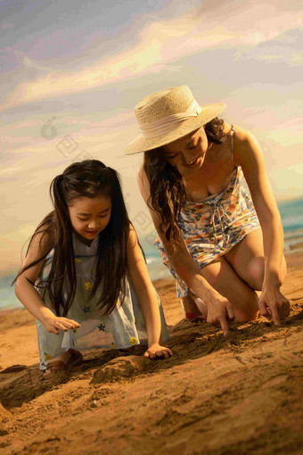 年轻妈妈带着女儿在沙滩上玩耍