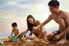 快乐的三口之家在沙滩上玩耍