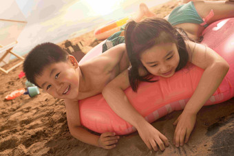 沙滩上的快乐东方<strong>儿童</strong>趴在游泳圈上玩耍