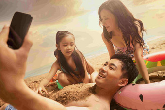 沙滩上男人拿<strong>手机</strong>和妻子孩子自拍