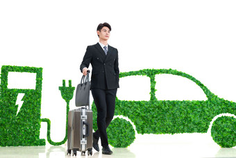 青年男士推着行李箱走在电动汽车旁绿色出行清晰照片