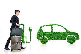 青年男士推着行李箱走在电动汽车旁绿色高端镜头
