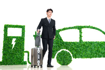 青年男士推着行李箱走在电动汽车旁绿色出行高端图片