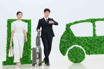 商务人士推着行李箱走在电动汽车旁商务旅行高质量素材