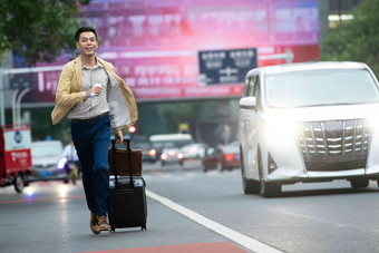 马路上拉着行李追赶汽车的商务男子笑氛围摄影图