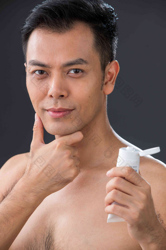 拿着剃须膏用手触摸下巴的男人微笑的高清影相