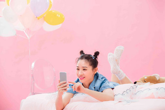 年轻女孩趴着在床上使用手机青年人高清场景