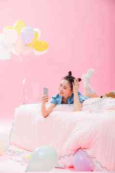 年轻女孩趴着在床上使用手机