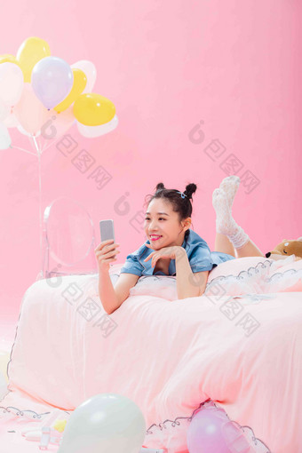 年轻女孩趴着在床上使用手机趴着高端摄影