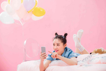年轻女孩趴着在床上使用手机一个人高端图片