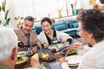 聚餐时中年男士给朋友倒红酒幸福高质量图片