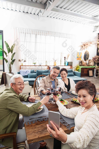聚餐时中老年人拿手机自拍室内氛围相片