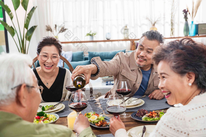 聚餐时中年男士给朋友倒红酒友谊清晰场景