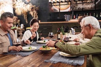 快乐的中老年朋友聚餐时边吃饭边聊天餐厅氛围照片