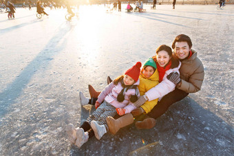 快乐的一家四口坐在冰面上玩耍