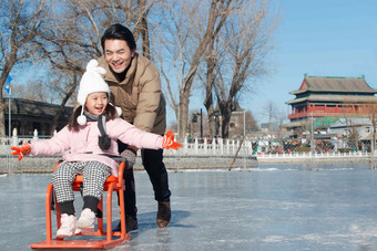 父亲带着女儿坐冰车玩耍