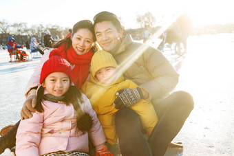 快乐的一家四口坐在溜冰场玩耍寒冷的高端图片