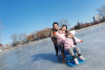 快乐的一家三口坐冰车玩耍青年男人氛围摄影图