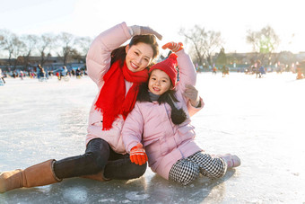 年轻妈妈和孩子在滑冰场玩耍寒冷的清晰影相