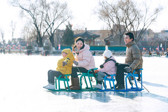 快乐的一家四口坐冰车玩耍寒冷的清晰照片
