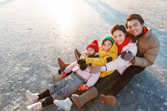 快乐的一家四口坐在冰面上玩耍