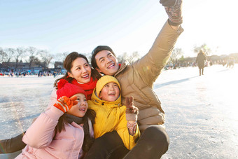 快乐的一家四口坐在溜冰场玩耍中国人氛围场景