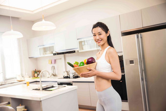 穿着运动装的青年女人在厨房饮食高清照片