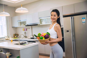 穿着运动装的青年女人在厨房水果氛围图片