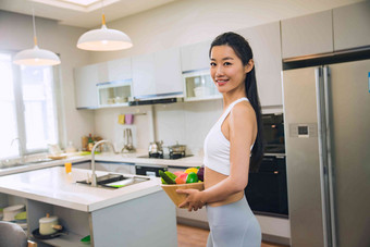 穿着运动装的青年女人在厨房蔬菜写实镜头