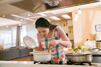 青年女人在厨房煲汤家务劳动写实摄影图