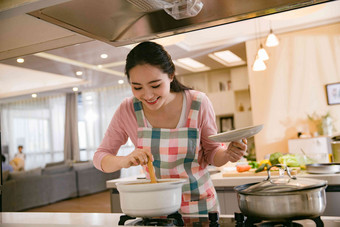 青年女人在厨房煲汤白昼图片