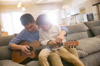 父亲和男孩在弹吉他户内高清场景