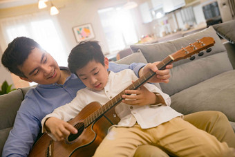 父亲和男孩在弹吉他享乐氛围相片