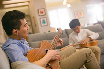 父亲和男孩在弹吉他放松清晰摄影图