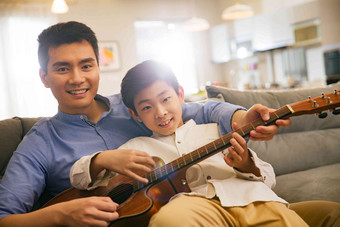 父亲和男孩在弹吉他放松高端摄影图
