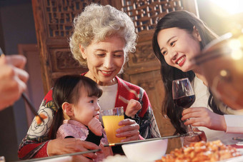 青年女人带女儿陪母亲用餐坐着写实照片