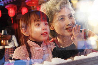 小女孩和祖母看向窗外除夕摄影图