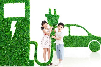 快乐的东方儿童给新能源汽车充电树叶氛围拍摄