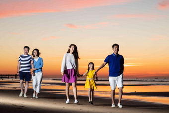 夕阳下在海边散步的幸福家庭