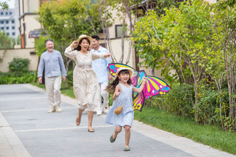 拿着风筝的小女孩和家人在<strong>户外</strong>玩耍