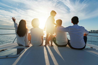 夕阳下坐在游艇上的快乐一家人
