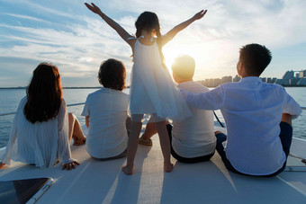 夕阳下坐在游艇上的快乐一家人
